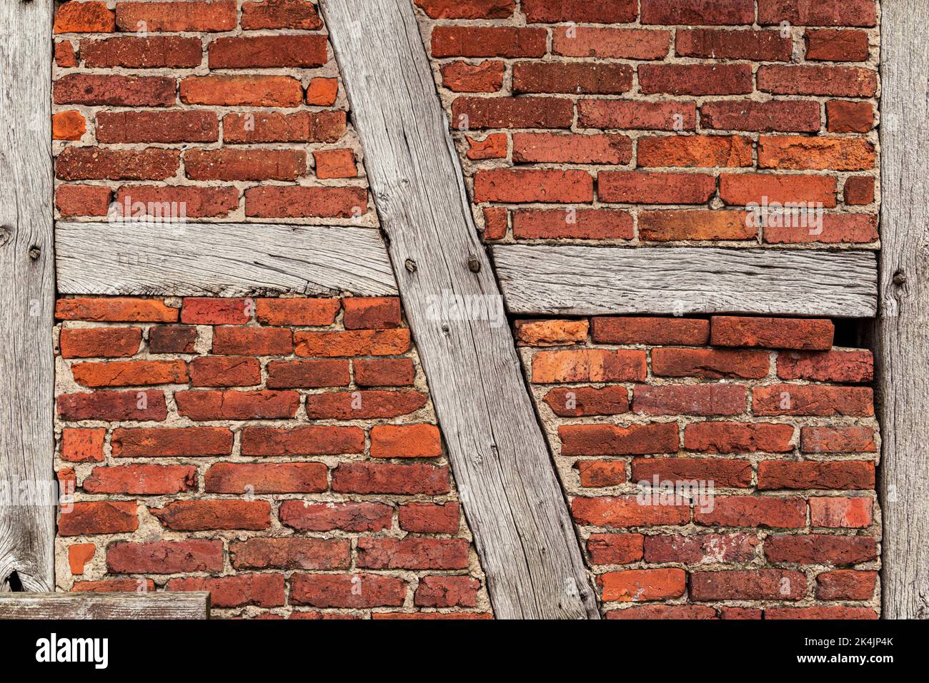Trama di fondo di una vecchia parete in legno, costituita da travi in legno intemperie e mattoni rossi di bakestone, tipico per architettura a graticcio Foto Stock