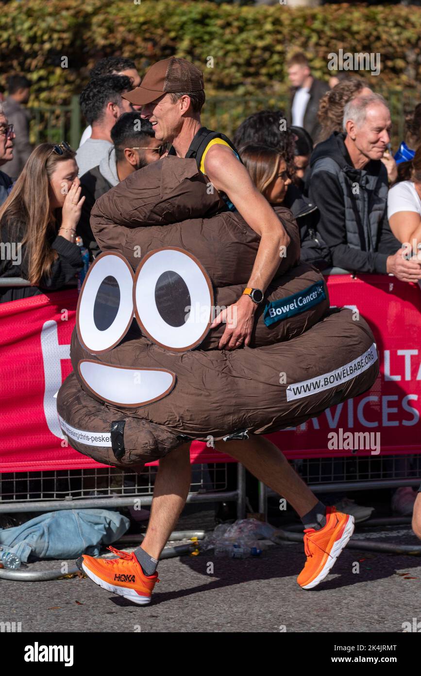 Chris Peskett corre nella TCS London Marathon 2022, sulla Tower Hill Road, City of London, UK. Indosso il costume da poo per l'associazione di beneficenza di Bowel Cancer UK Foto Stock