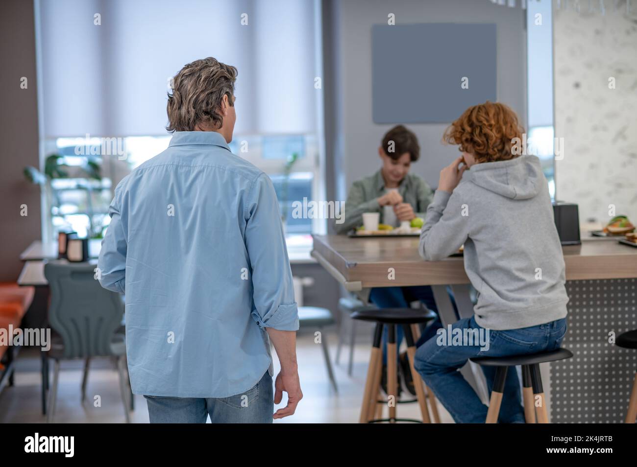 Insegnante che parla con i suoi allievi durante l'ora di pranzo Foto Stock