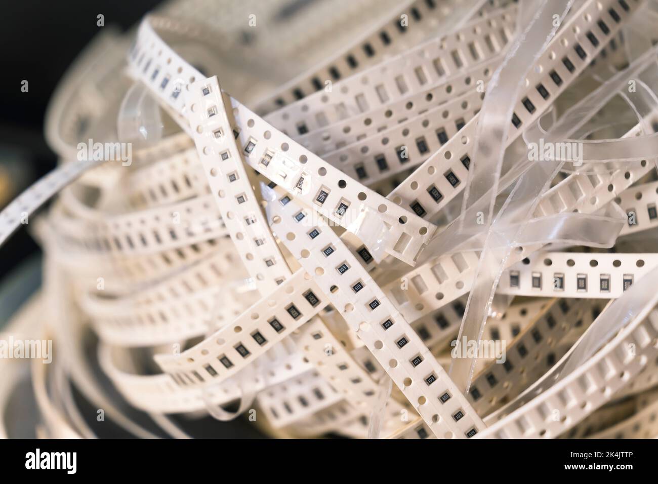 Fascio di nastro bianco aggrovigliato con componenti della scheda a circuito stampato elettrica SMD da assemblare. Montaggio superficiale. Foto di alta qualità Foto Stock