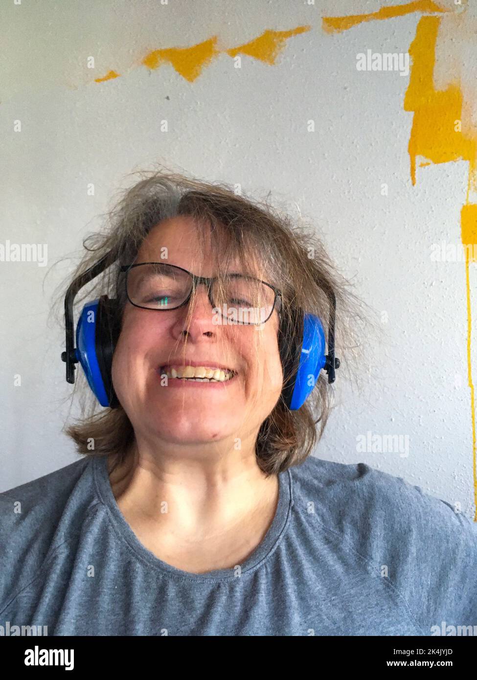 Frau mit Kopfhörer mit zerzausten Haaren, genervt vom Lärm Foto Stock