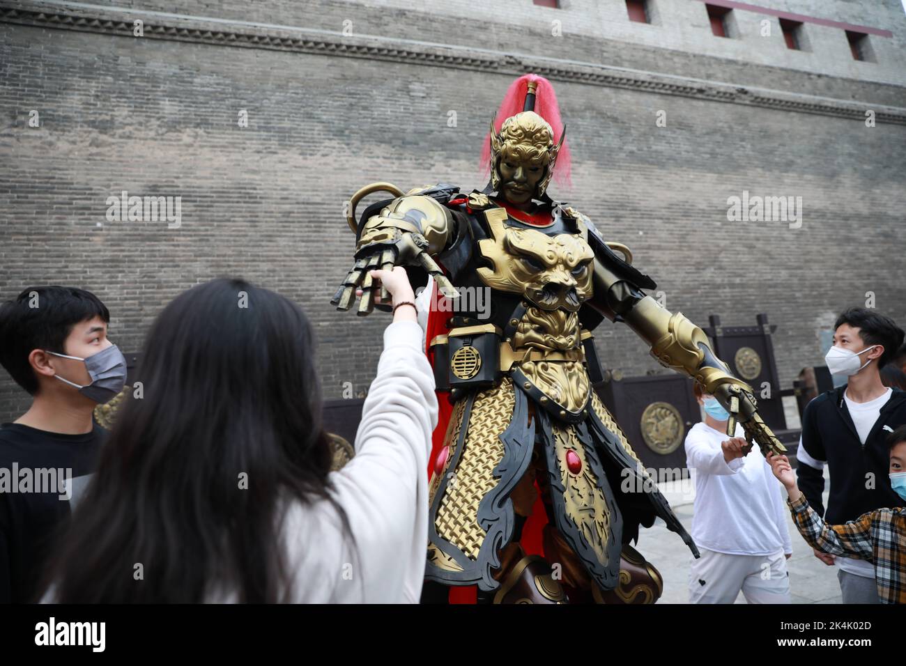 XI'AN, CINA - 1 OTTOBRE 2022 - i turisti posano con un 'Guerriero' di Mecha 2,7 metri di altezza navigando alla porta di Yongning del Muro della città di Xi'an a Xi'an, Shaanxi Foto Stock