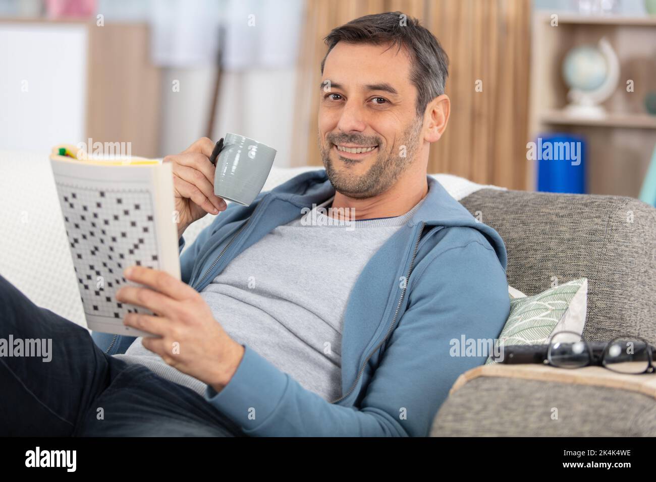 l'uomo sta leggendo una rivista che tiene una tazza di caffè Foto Stock