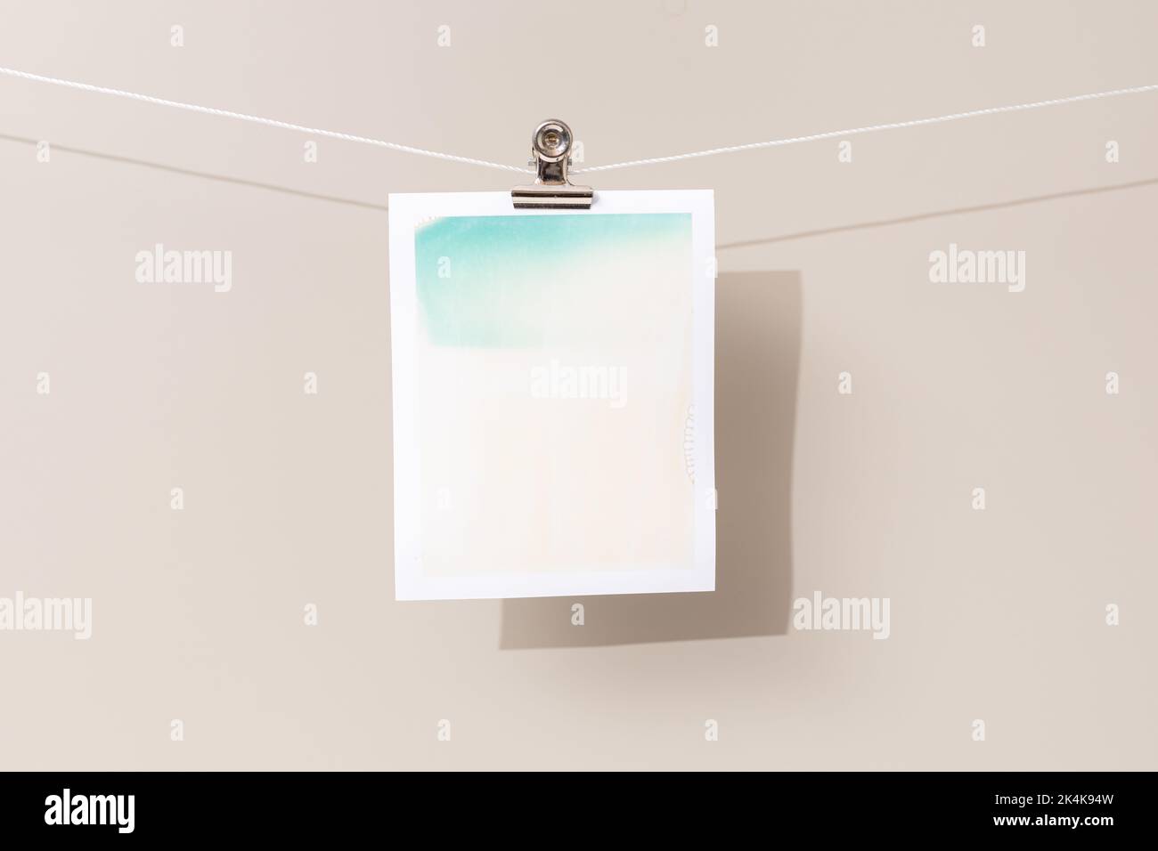 cornice fotografica istantanea con macchie verdi e beige appese su una corda Foto Stock