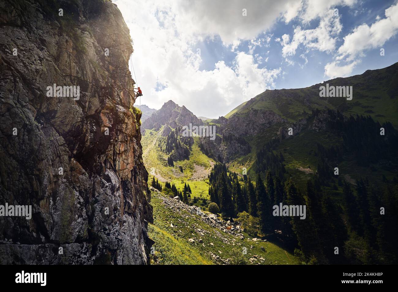 Adatta un atleta forte nella silhouette rock climbing sulla parete verticale alta sulle montagne Tyan Shan in Kazakistan Foto Stock