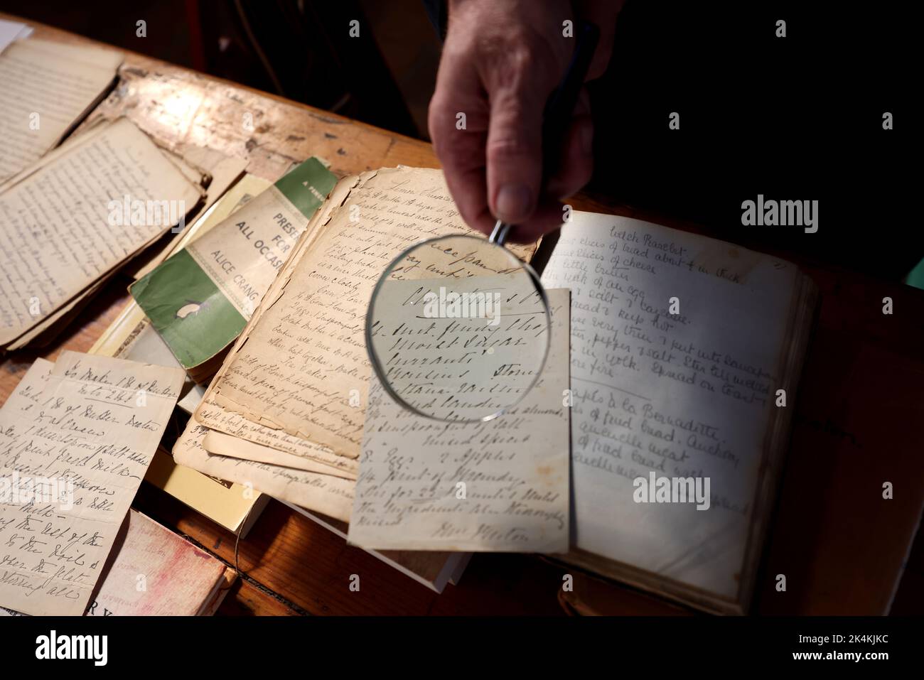 Libri in vecchio stile e una lente d'ingrandimento che mostrano la scrittura a mano del passato al Weald & Downland Museum, Chichester, West Sussex, Regno Unito. Foto Stock