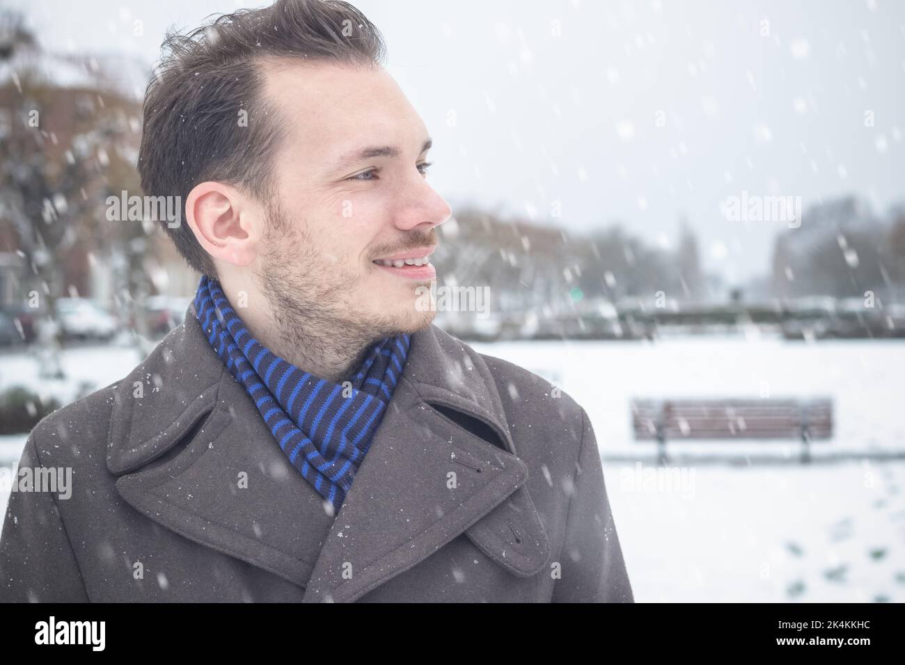 Ritratto di giovane bell'uomo con barba sorridente ridendo nella neve d'inverno Foto Stock