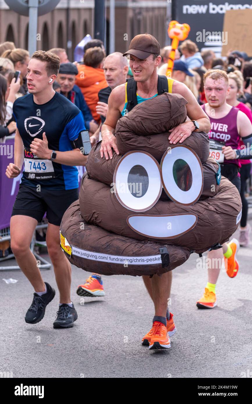 Chris Peskett correndo nella maratona di Londra di TCS 2022, sulla strada di avvicinamento di Tower Bridge, la città di Londra, Regno Unito, indossando il costume del poo per il cancro di Bowel Regno Unito Foto Stock