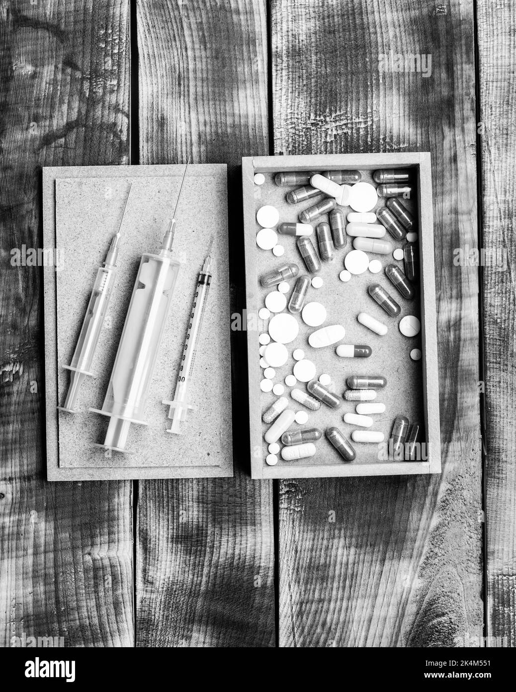 Pillole di farmaci e fiale di siringhe in scatola su sfondo di legno, kit di pronto soccorso Foto Stock