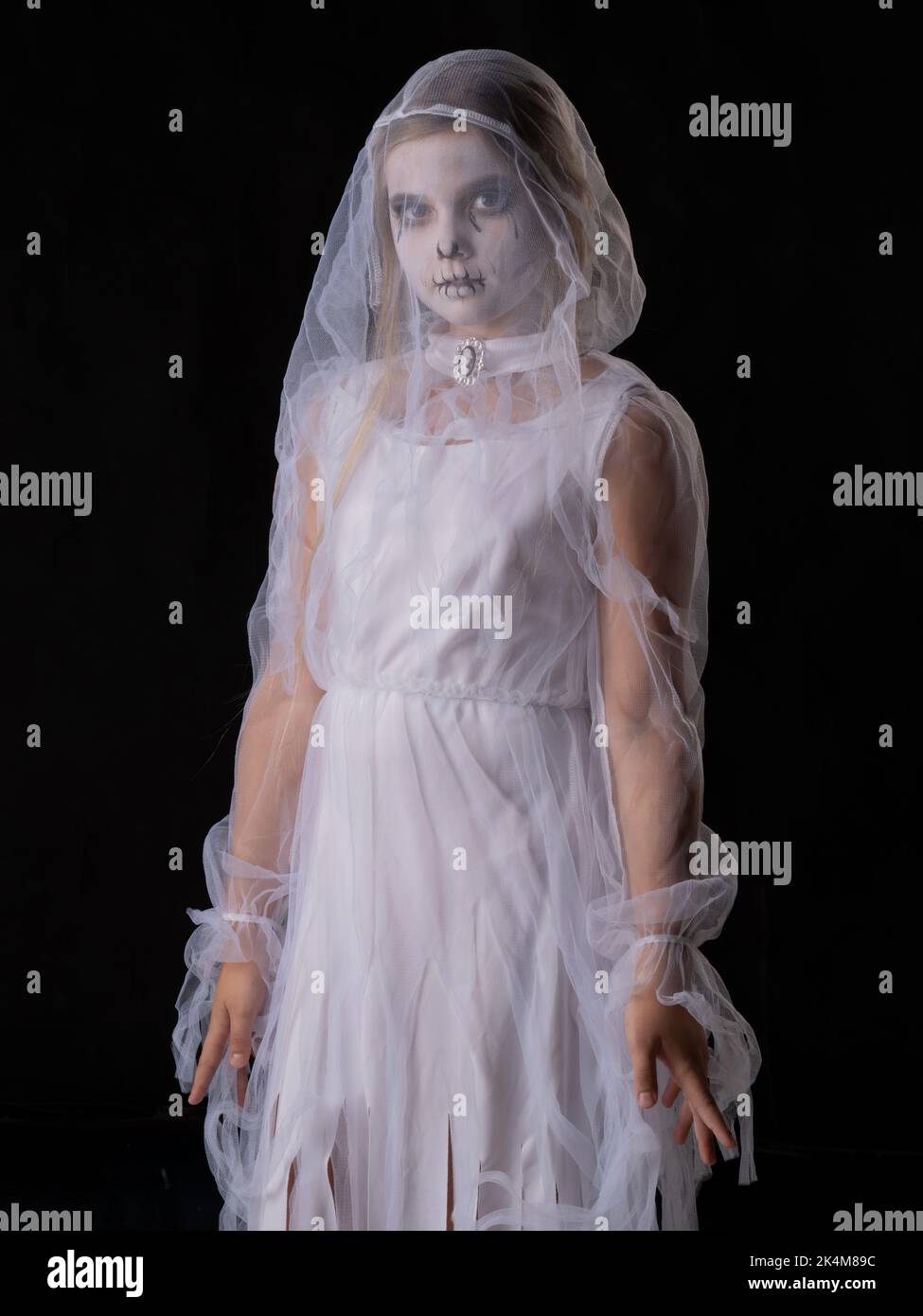 Bambina in costume fantasma di Halloween guardando la macchina fotografica, studio isolato su sfondo nero Foto Stock
