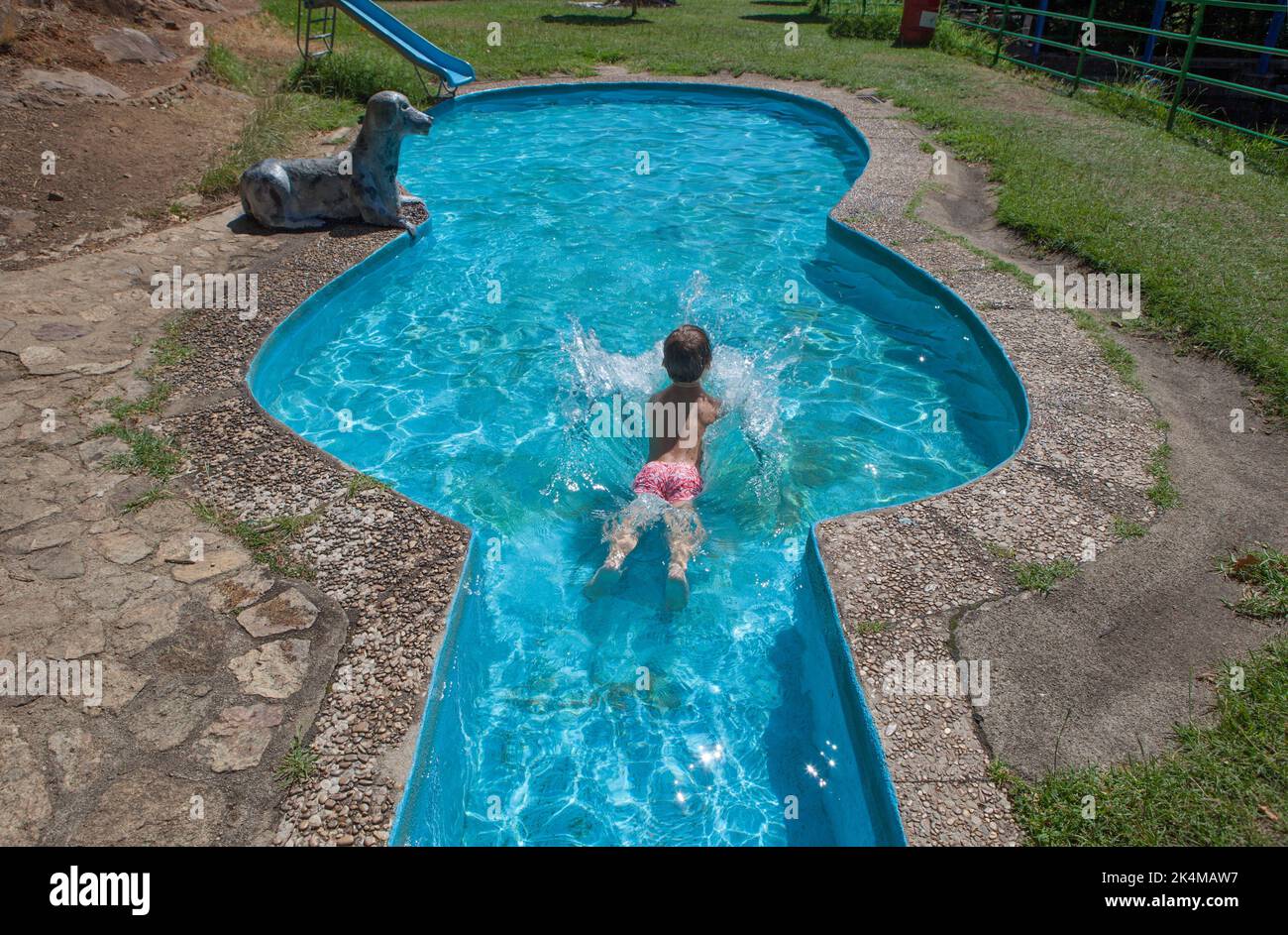 Bambino nella piscina a forma di chitarra accanto alla piscina naturale Vadillo. Losar de la vera, Caceres, Estremadura, Spagna. Foto Stock