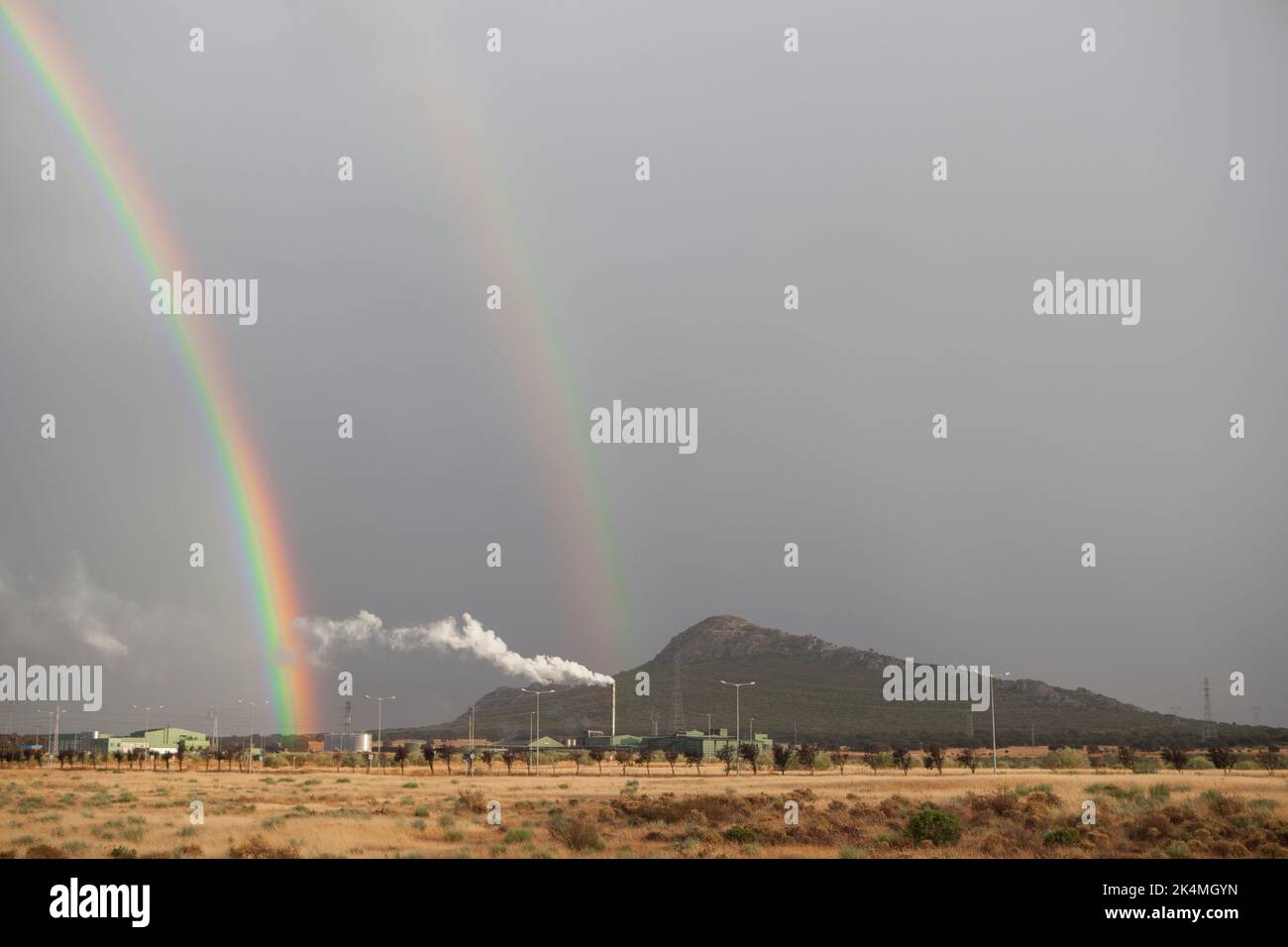 Doppio arcobaleno che sorge su un'area industriale. Sono visibili arcobaleni primari e secondari. Foto Stock