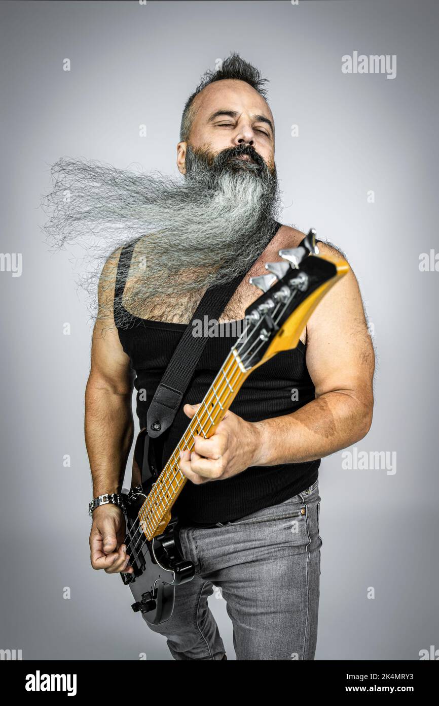 il bilanciere con la chitarra e la barba lunga suona con gli occhi chiusi. studio shot Foto Stock