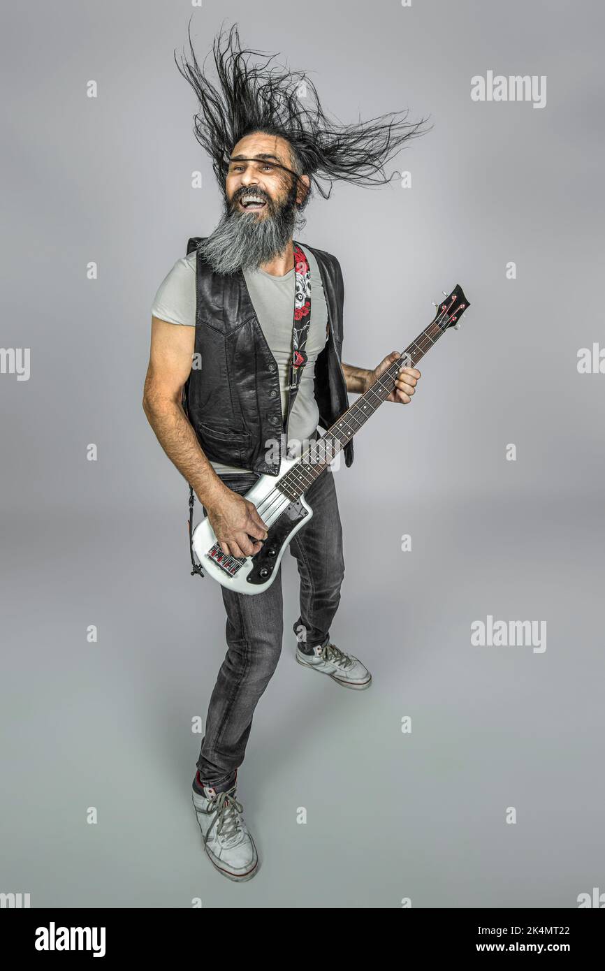 l'uomo con lunghi capelli svolazzanti suona la chitarra basso, ripresa in studio Foto Stock