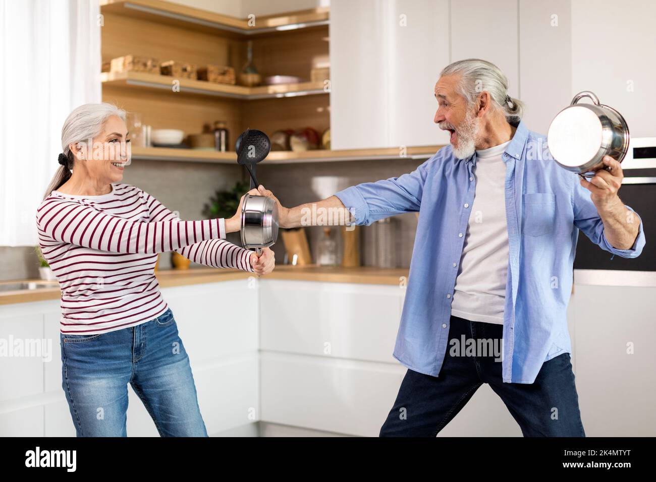 Ritratto di giocosa coppia anziana imbrogliante insieme in cucina interno Foto Stock