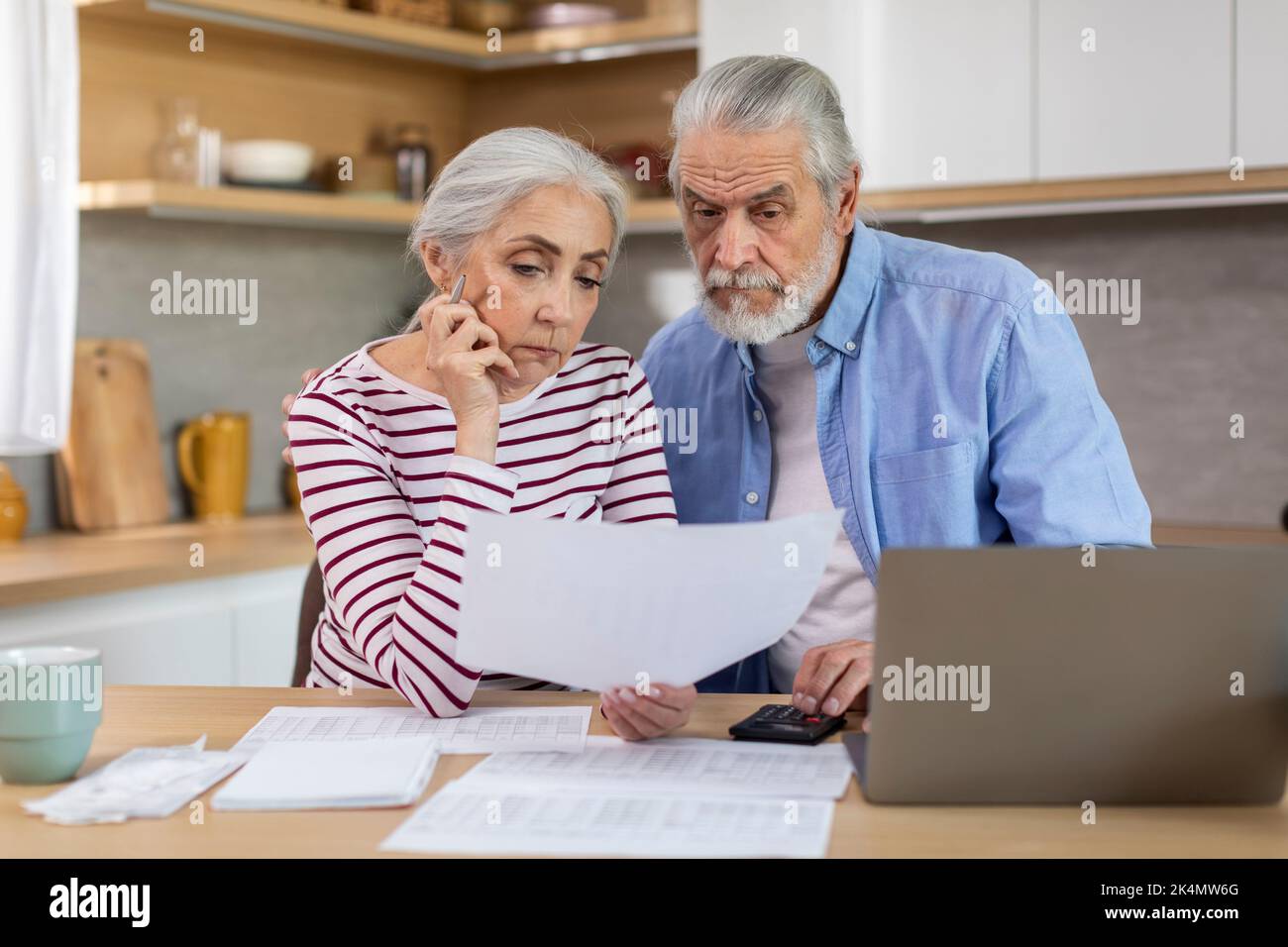 Sconvolgere la coppia anziana che verifica i documenti finanziari mentre calcola il bilancio della famiglia a casa Foto Stock