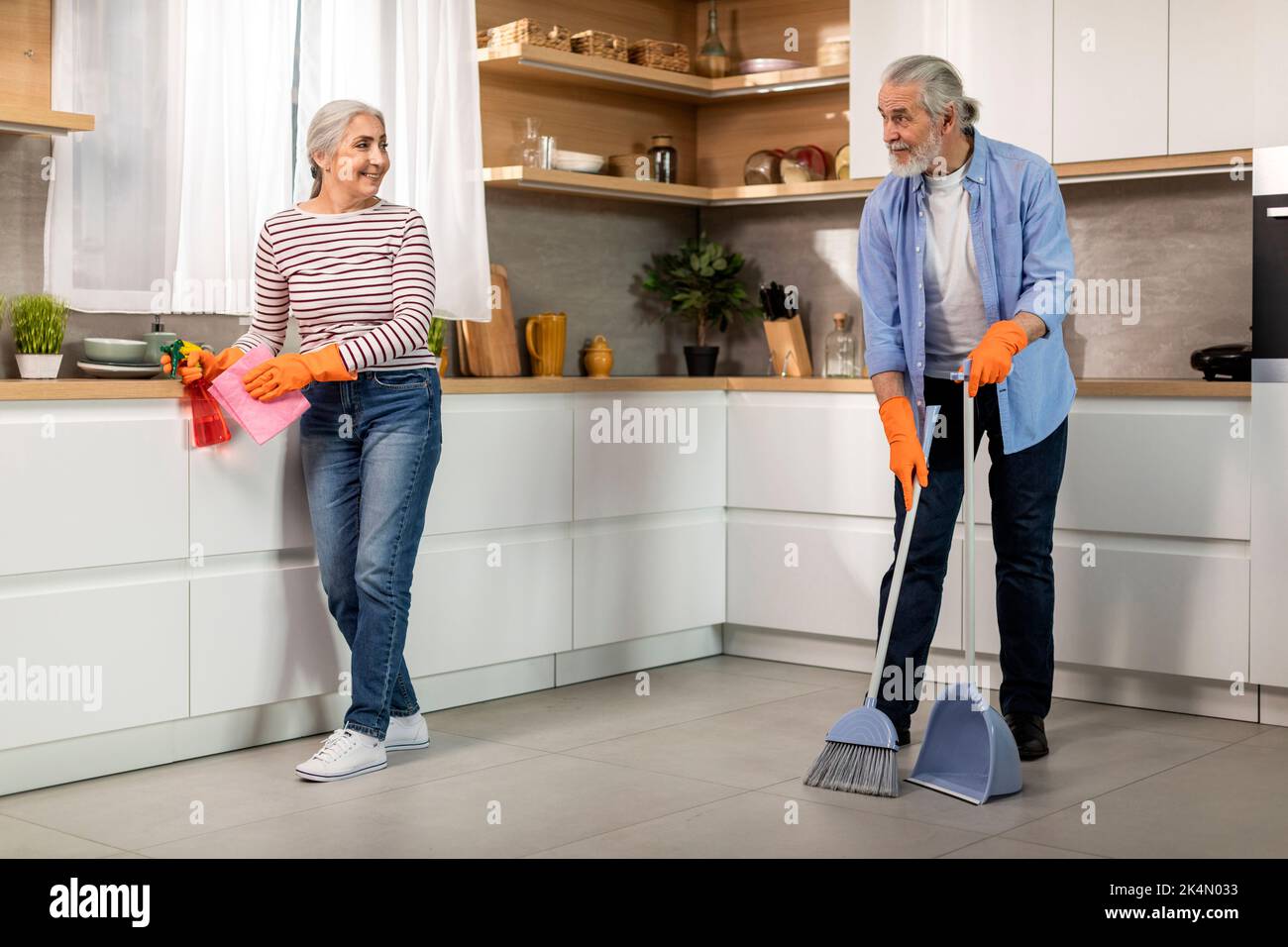 Ritratto di sposi anziani felici che fanno la pulizia in cucina insieme Foto Stock