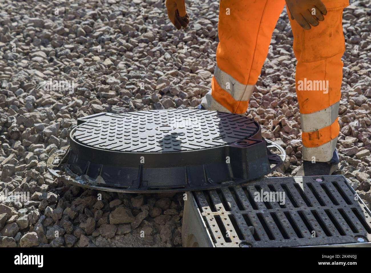 Lavoratore una posa di fognature acque di drenaggio pozzi fognari ricostruzione durante costruzione strada Foto Stock