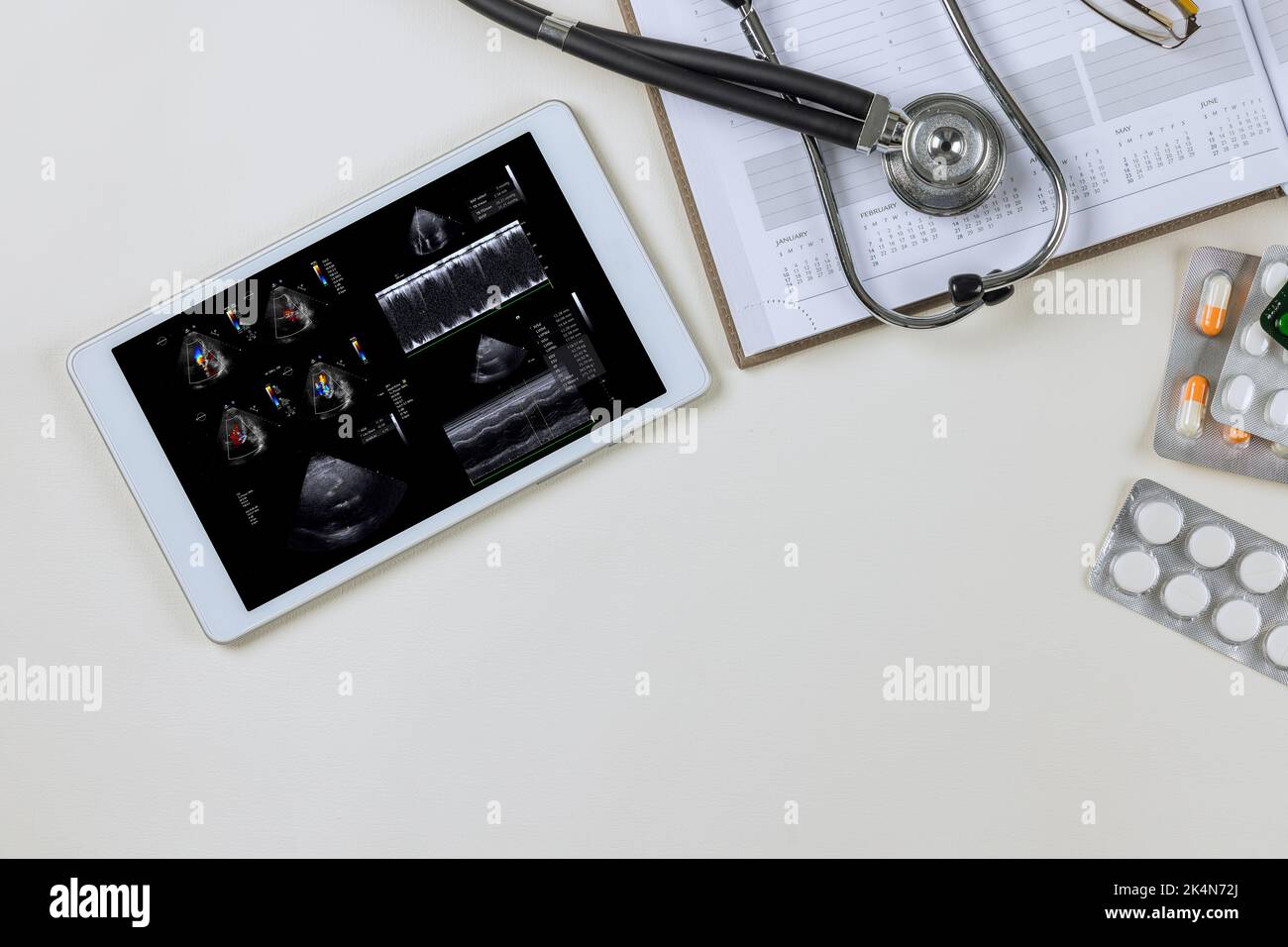 C'è un medico sulla tavoletta digitale che controlla i risultati dell'ecocardiografia per prescrivere un piano di trattamento efficace per Foto Stock