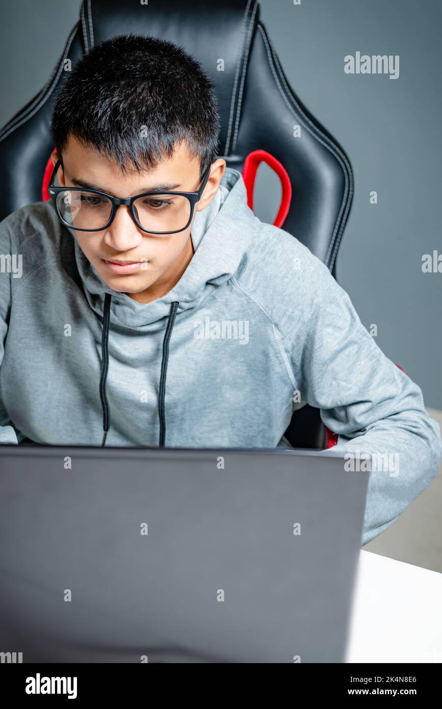 Teen adolager ragazzo casa scuola studiare stanza scrivania pc computer vetri seduta guardando i compiti Foto Stock