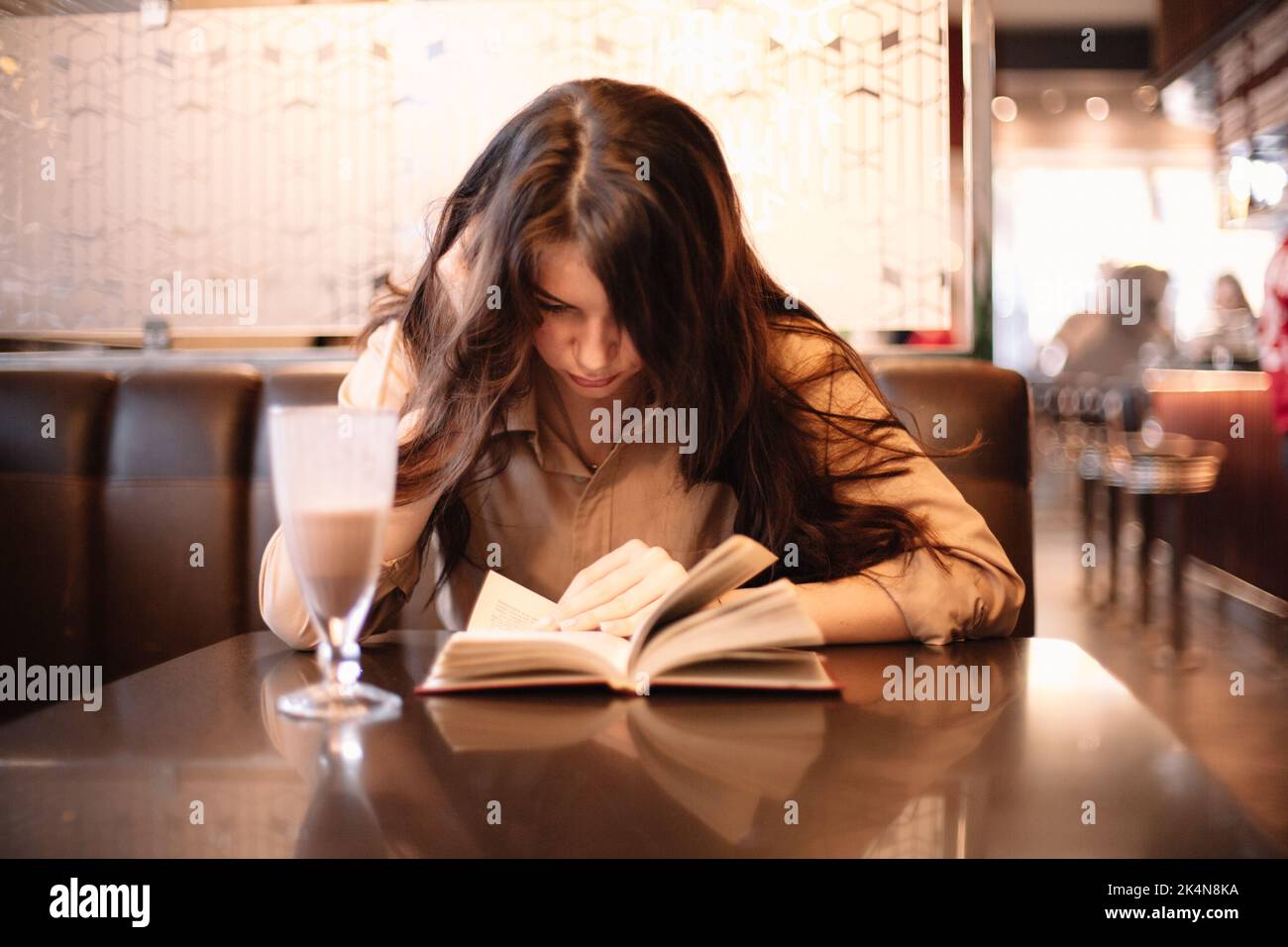 Ragazza adolescente leggere libro mentre si siede in caffè Foto Stock