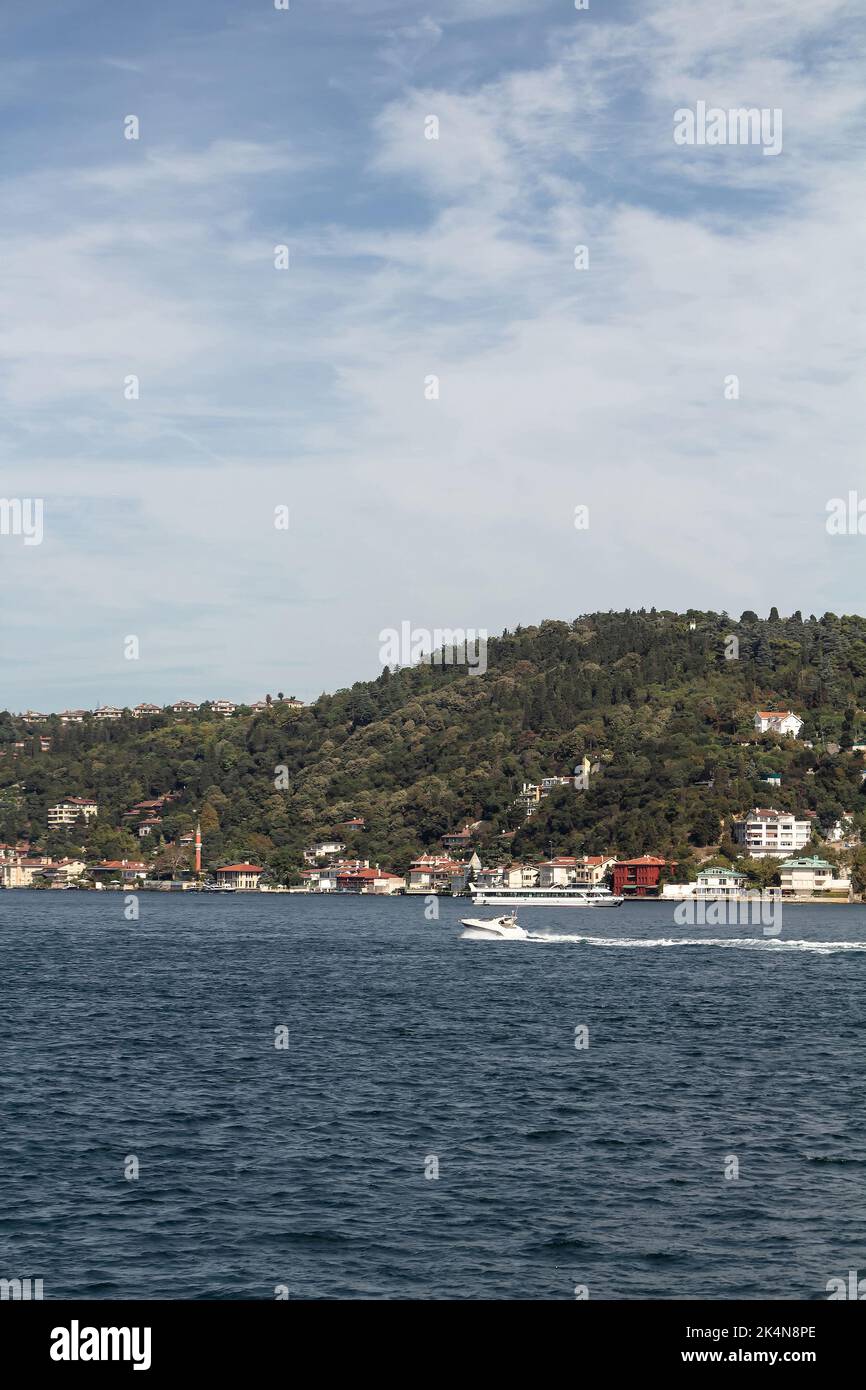 Vista di una piccola barca che passa sul Bosforo e sul lato asiatico di Istanbul. E' una giornata estiva di sole. Bella scena di viaggio. Foto Stock