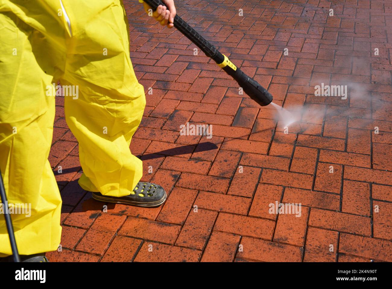 una donna pulisce la terrazza con un pulitore ad alta pressione Foto Stock
