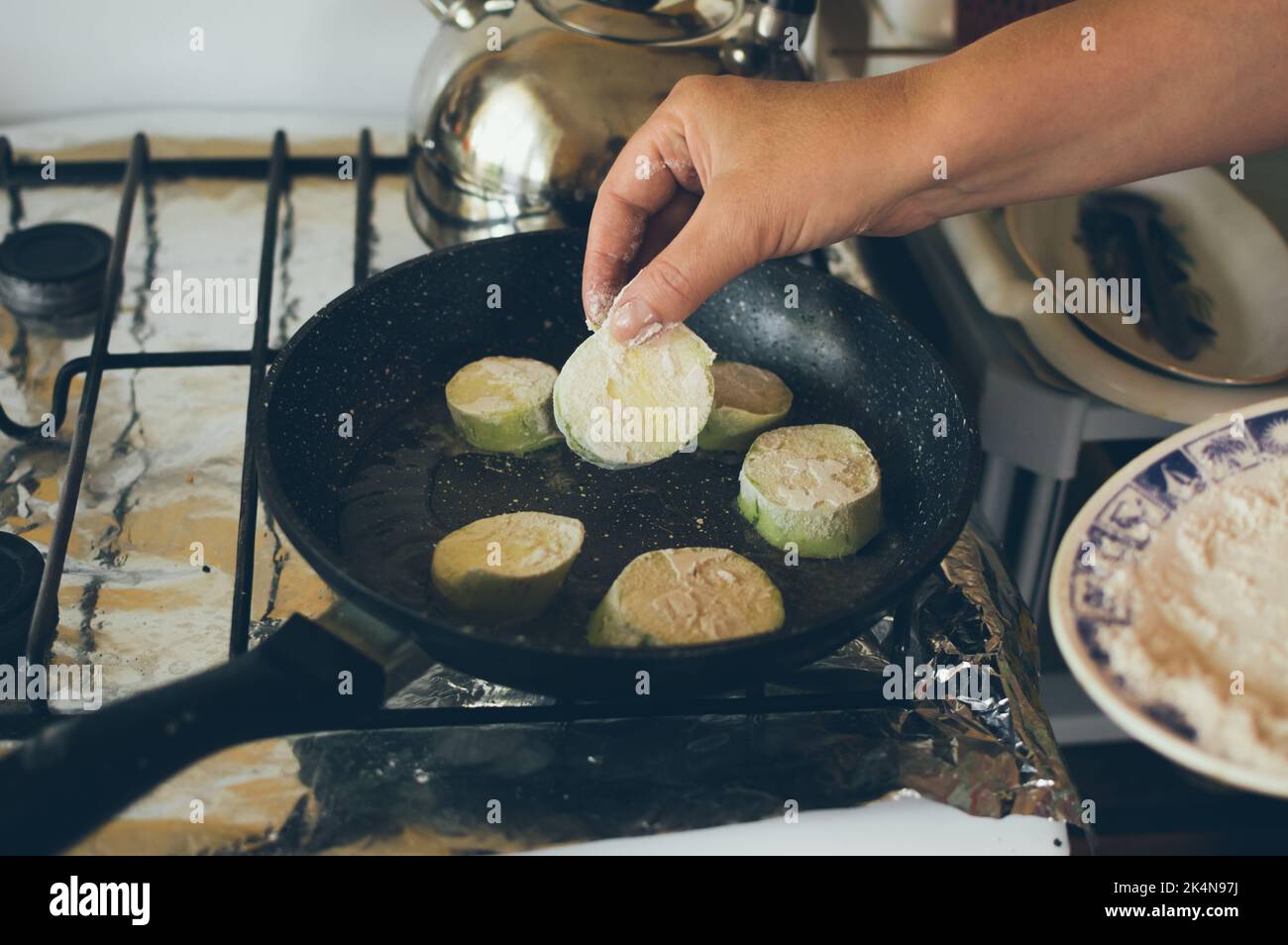 Friggere le zucchine verdi in farina in padella su stufa a gas Foto Stock