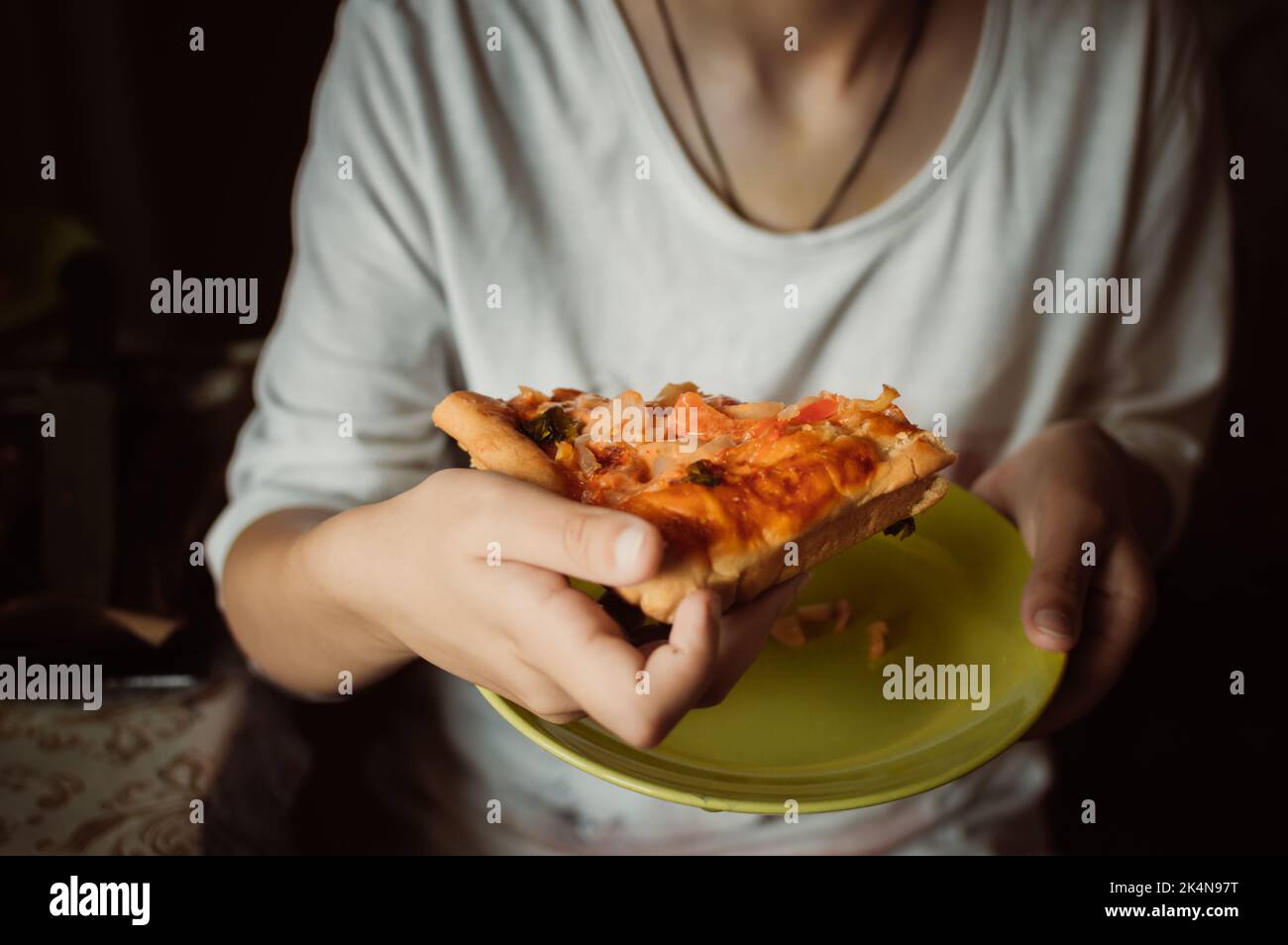 Le mani tengono un pezzo di deliziosa pizza fatta in casa con verdure Foto Stock