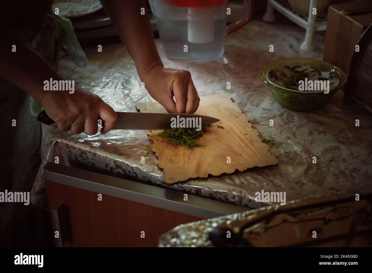 Donna taglia l'aneto verde sul tagliere di legno in cucina Foto Stock