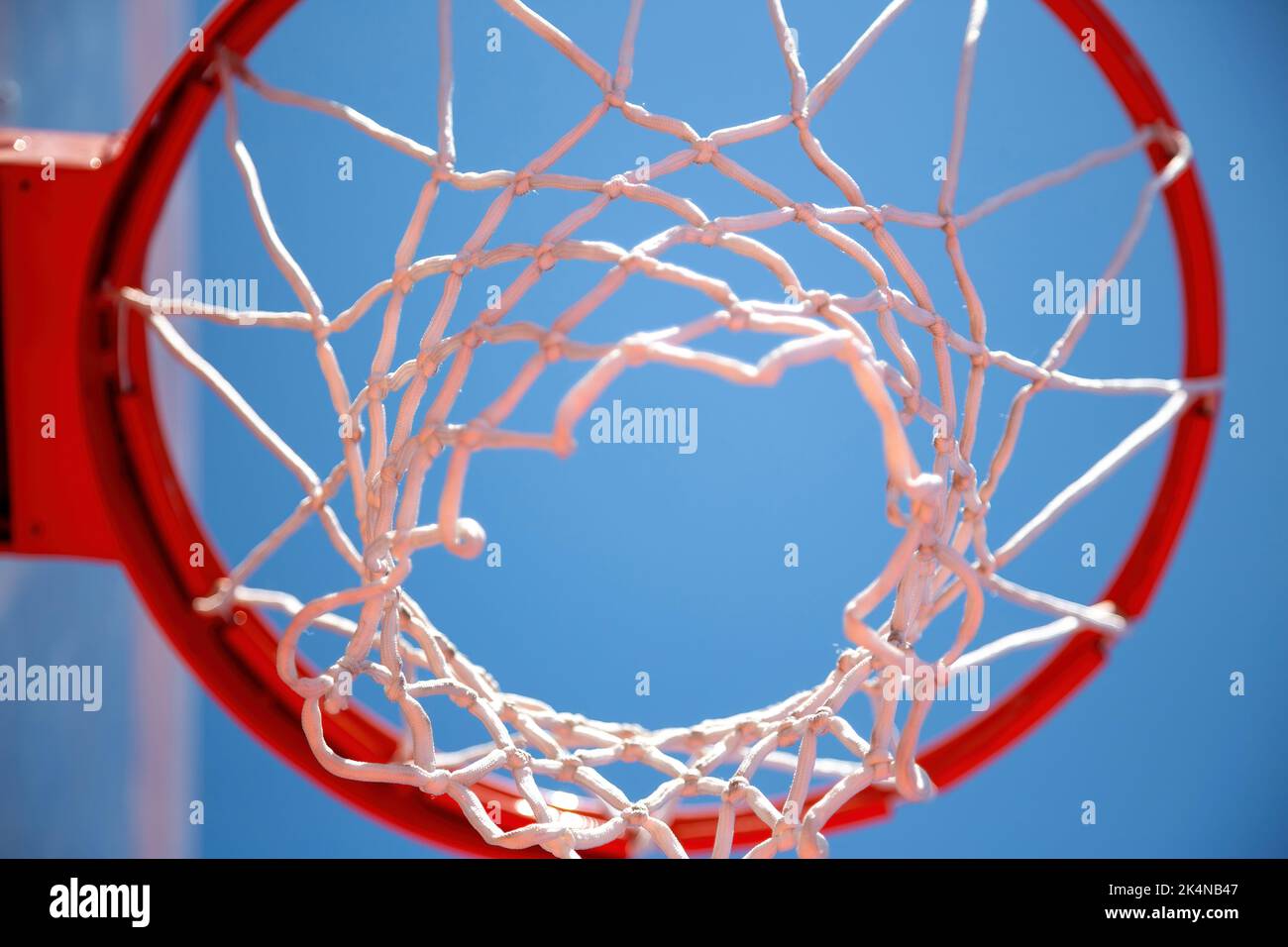 Canestro da basket, anello e rete rossi, sfondo cielo blu, vista dal fondo. Giorno di sole, campo sportivo all'aperto Foto Stock