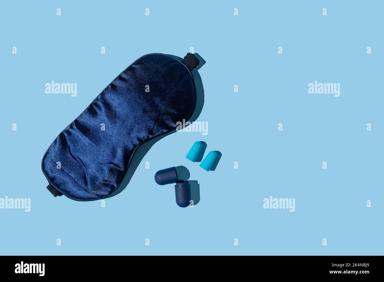 Concetto di sonno di qualità: Maschera di sonno blu e tappi per le orecchie su sfondo blu. Accessori per un buon riposo notturno, blocco di qualsiasi luce e suono. Foto Stock