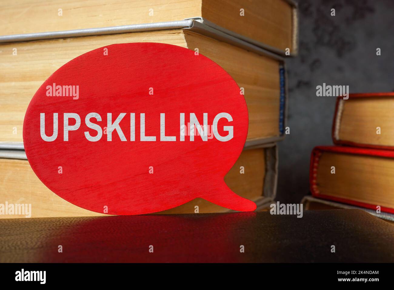 Pila di libri e piatto con parola upskilling. Foto Stock