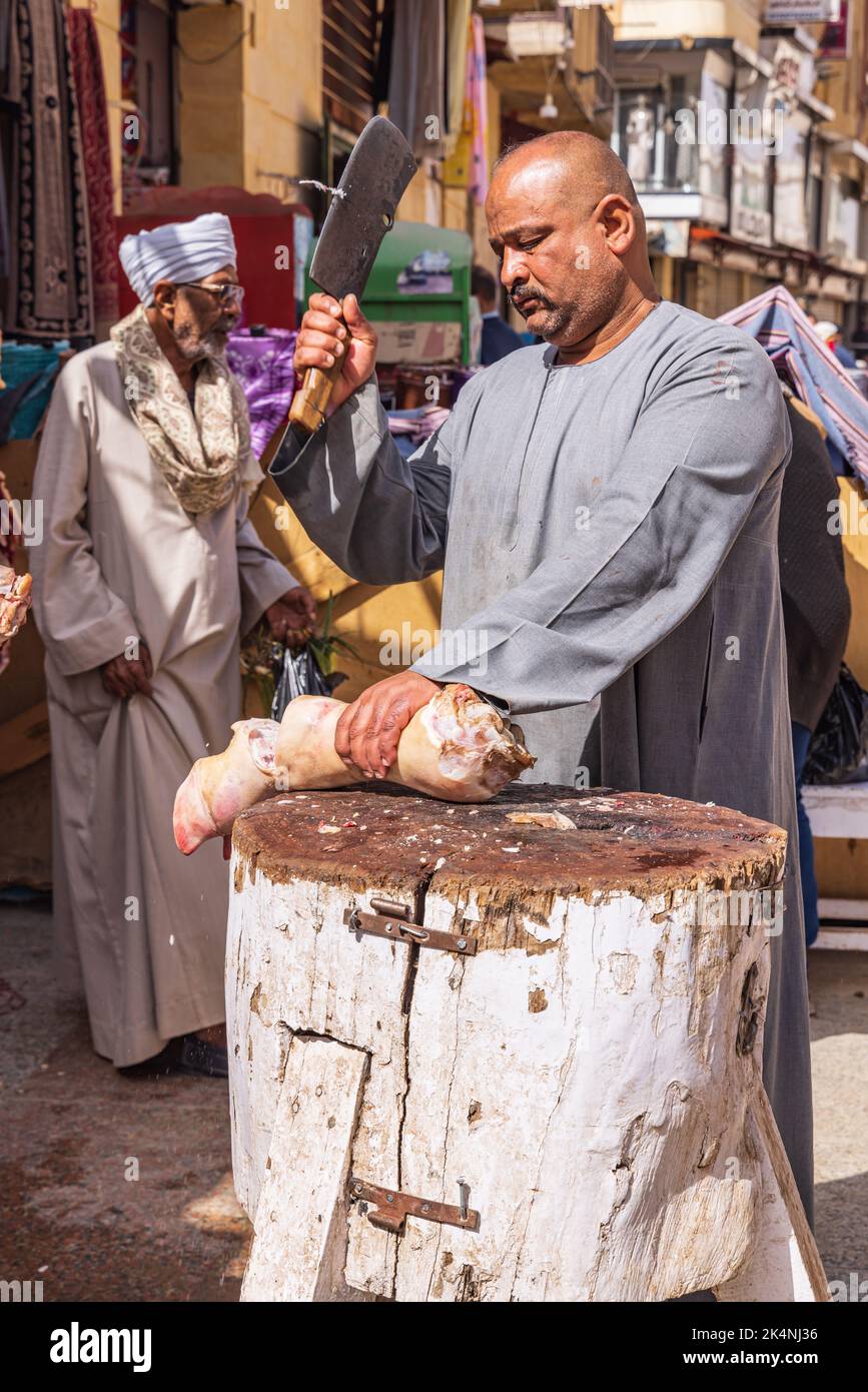 Tebe, Luxor, Egitto. Febbraio 24, 2022. Macellaio tritare un piede di mucca su un blocco di macellaio esterno. Foto Stock