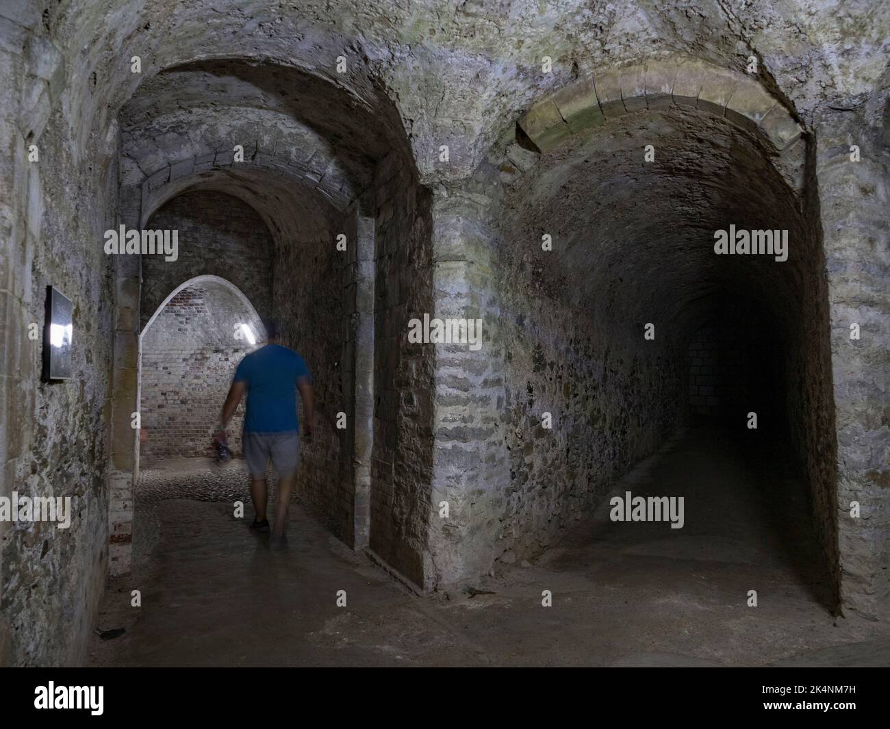 Visitatore all'interno dei tunnel medievali sotto dover Castle, Kent, Regno Unito. Foto Stock
