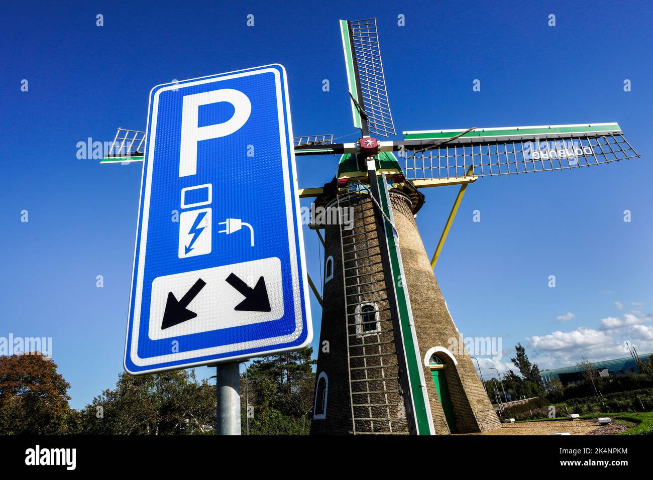 Elettricità da energia eolica: Parcheggio con punto di ricarica per veicoli elettrici di fronte allo storico mulino a vento dal 1817 a Domburg, nei Paesi Bassi Foto Stock