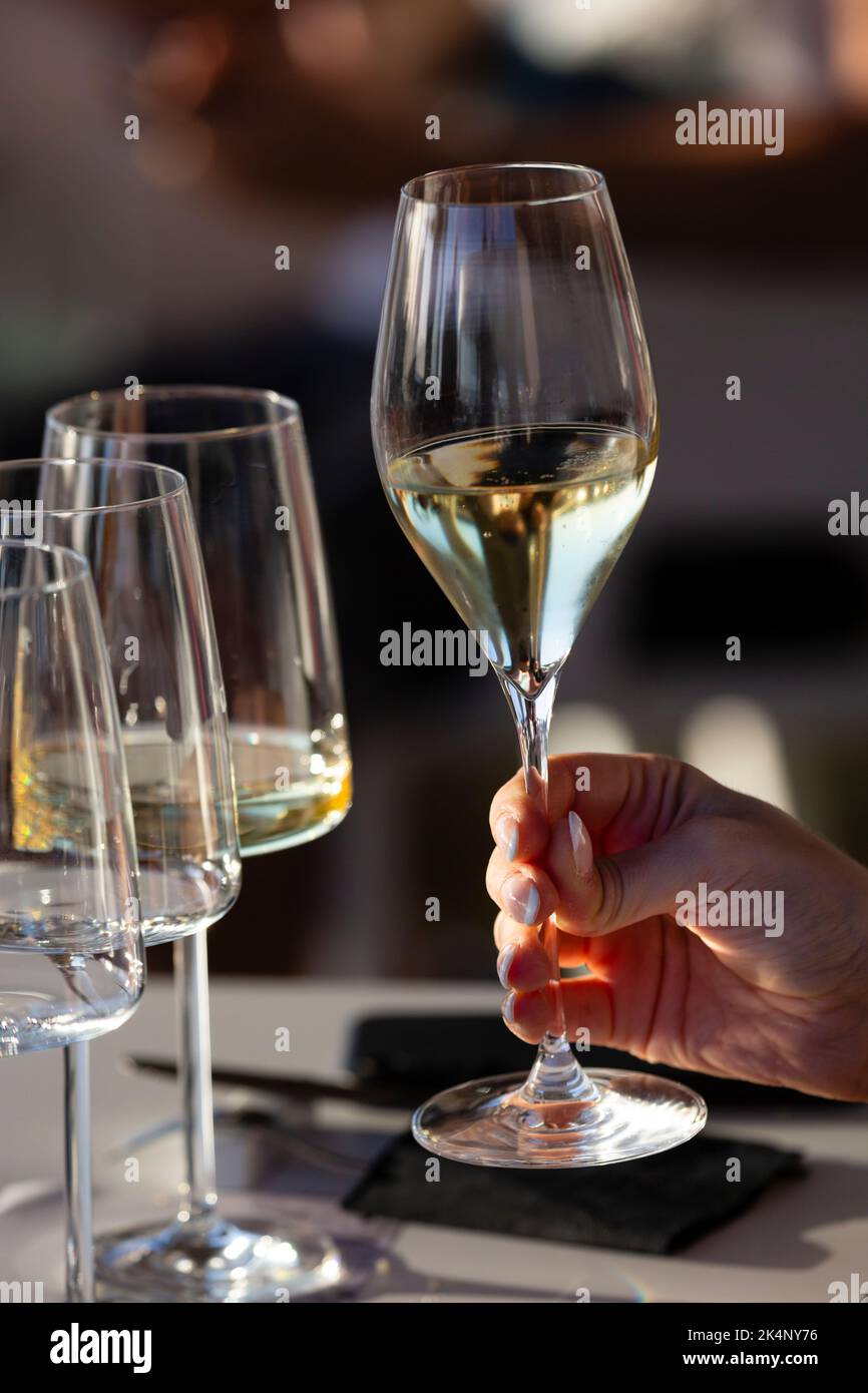 Una mano destra tiene un bicchiere di cristallo con vino bianco Foto Stock