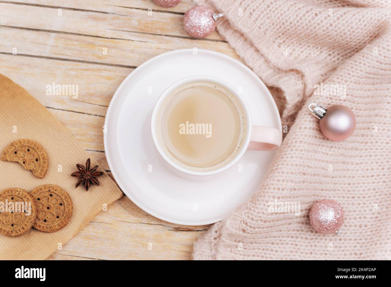 Una tazza di latte di caffè, biscotti fatti in casa e palle di Natale su un maglione lavorato a maglia. Concetto di vacanza invernale. Vista dall'alto, disposizione piatta. Foto Stock