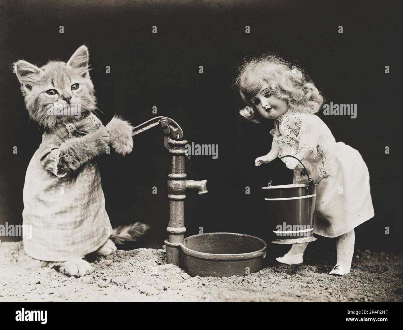 Un gattino che indossa abiti e che pompa acqua per una bambola, in una fotografia chiamata, 'Pumping' da Harry Whittier libera Foto Stock