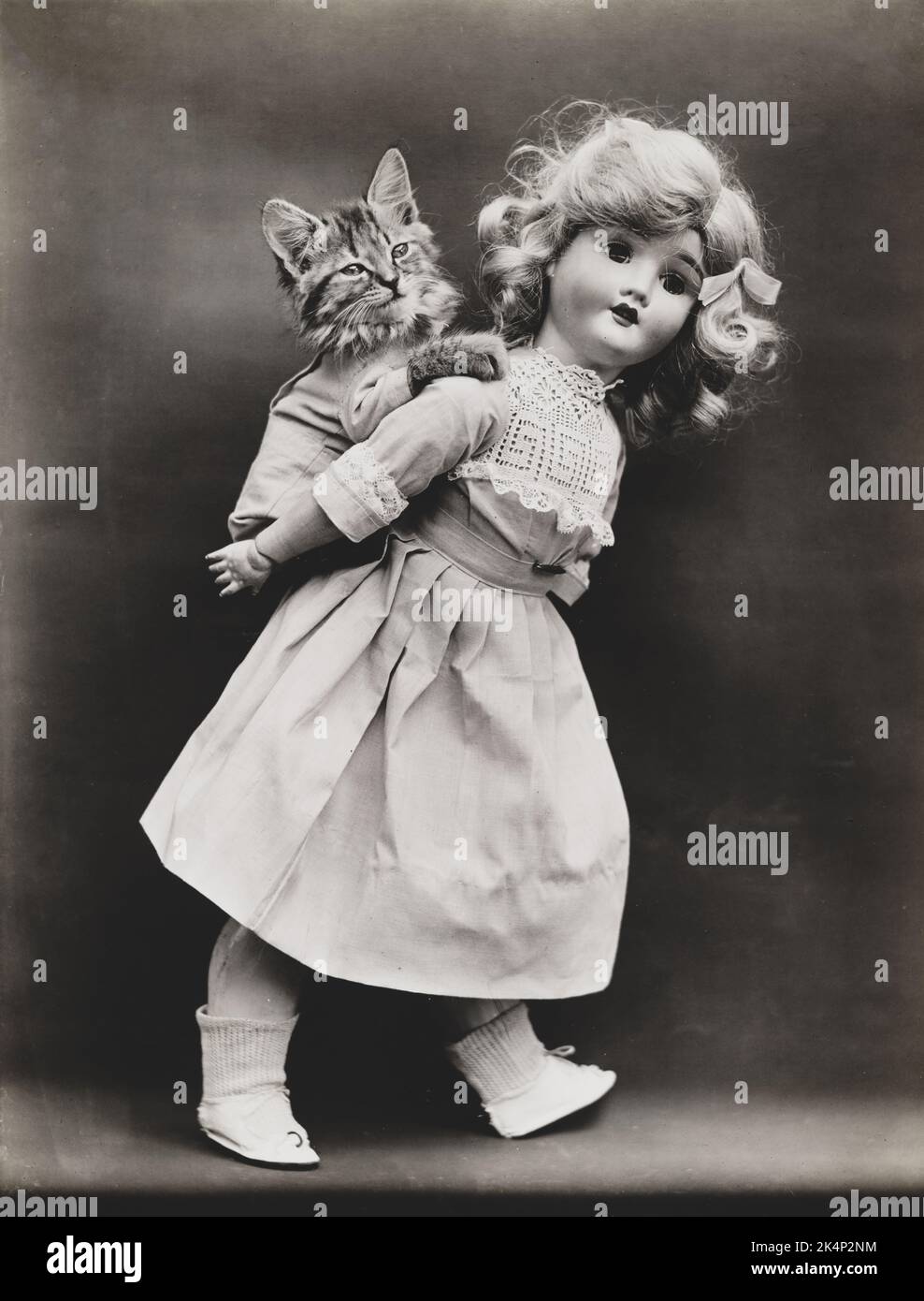 Un gattino che indossa abiti ottiene un piggy-back da una bambola, in una fotografia chiamata, 'pick-a-pack' da Harry Whittier libera Foto Stock