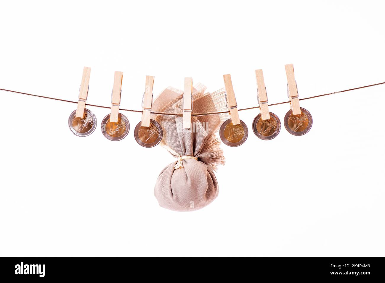 Monete su corda su sfondo bianco, banconote in euro, appese a vestiti appesi in legno. Asciugatura del denaro pulizia o riciclaggio. Denaro catturato da Foto Stock
