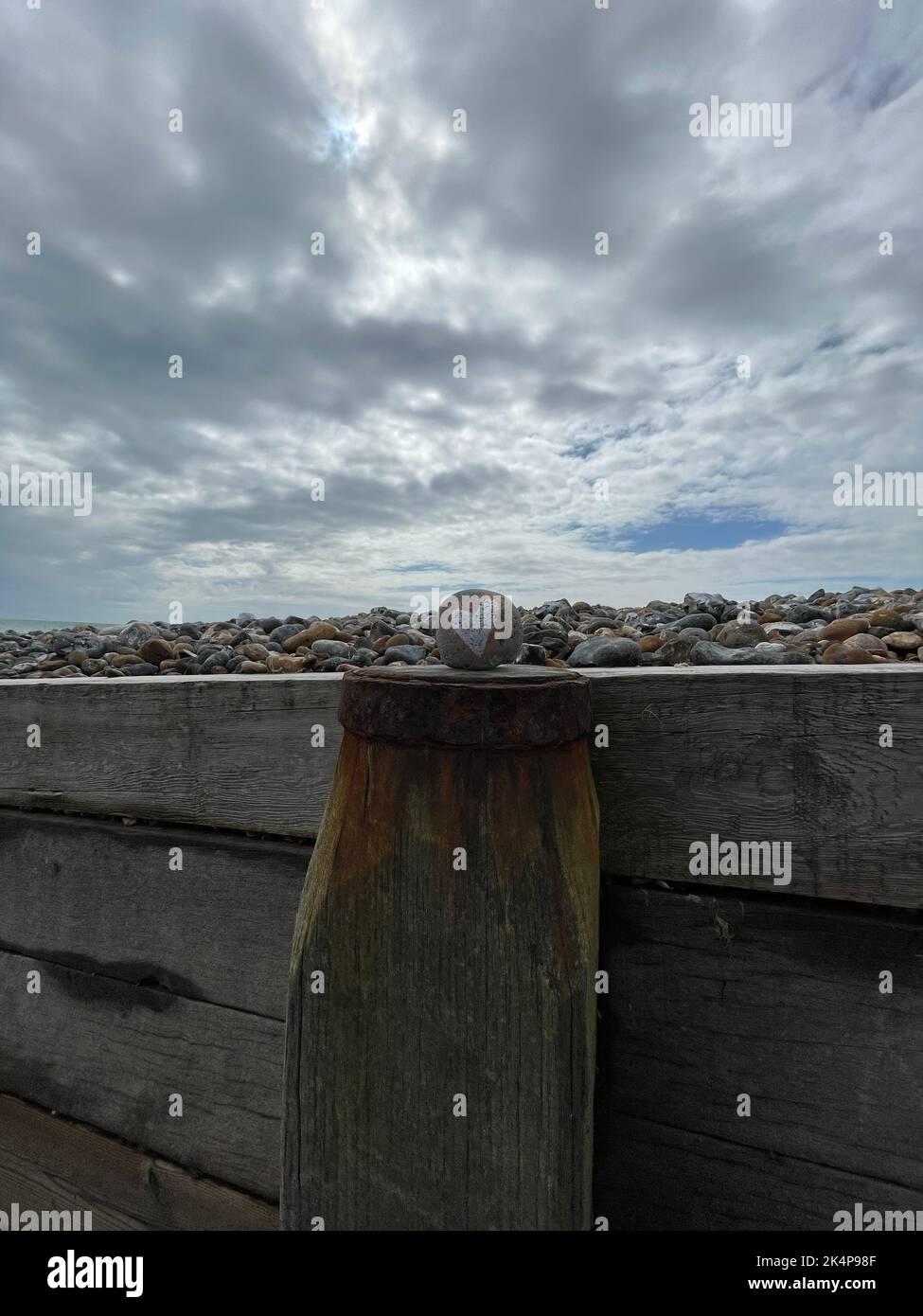 Uno scatto verticale di una roccia dipinta a cuore su una recinzione su una spiaggia inglese Foto Stock