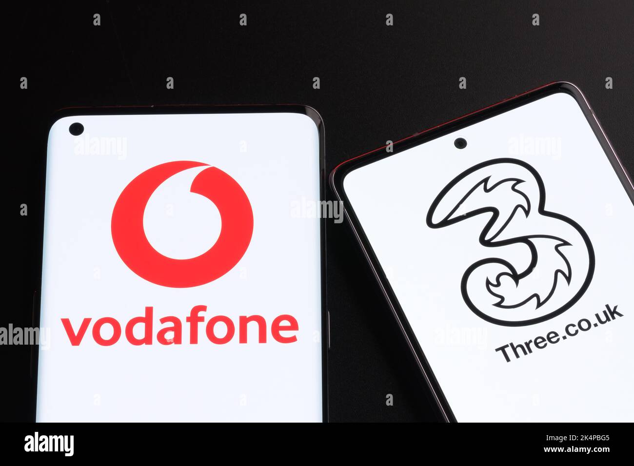 Vodafone e tre potenziali concetti di fusione. Gli smartphone visualizzati insieme ai logo degli operatori mobili del Regno Unito sulle schermate. Stafford, Regno Unito, Oc Foto Stock