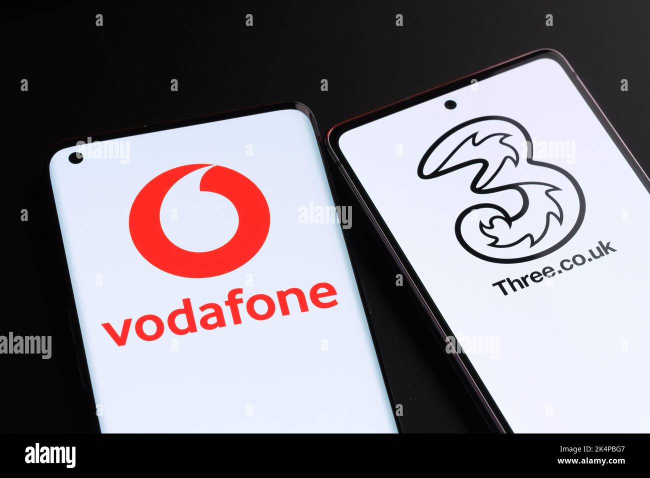 Vodafone e tre potenziali concetti di fusione. Gli smartphone visualizzati insieme ai logo degli operatori mobili del Regno Unito sulle schermate. Stafford, Regno Unito, Oc Foto Stock