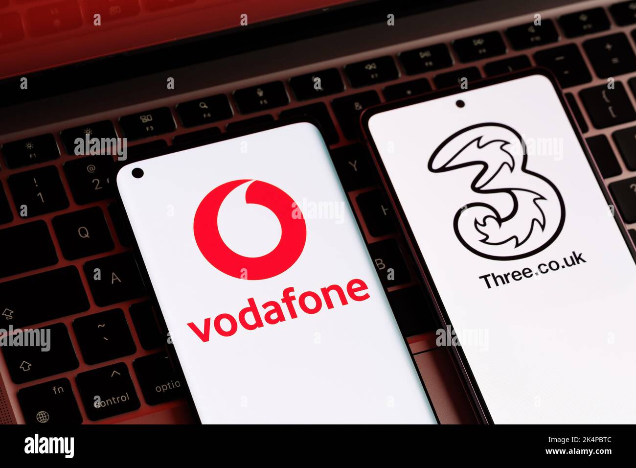 Vodafone e tre potenziali concetti di fusione. Gli smartphone visualizzati insieme ai logo degli operatori mobili del Regno Unito sulle schermate. Stafford, Regno Unito, Oc Foto Stock