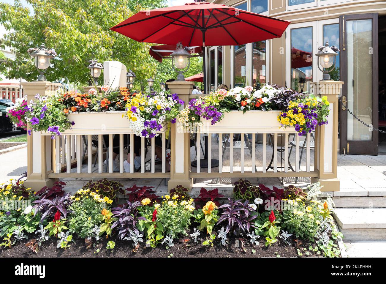 Ristorante con spazio all'aperto con posti a sedere sul patio che serve cibo per i clienti. Piante come decorazione e ombrelli per ombreggiatura Foto Stock