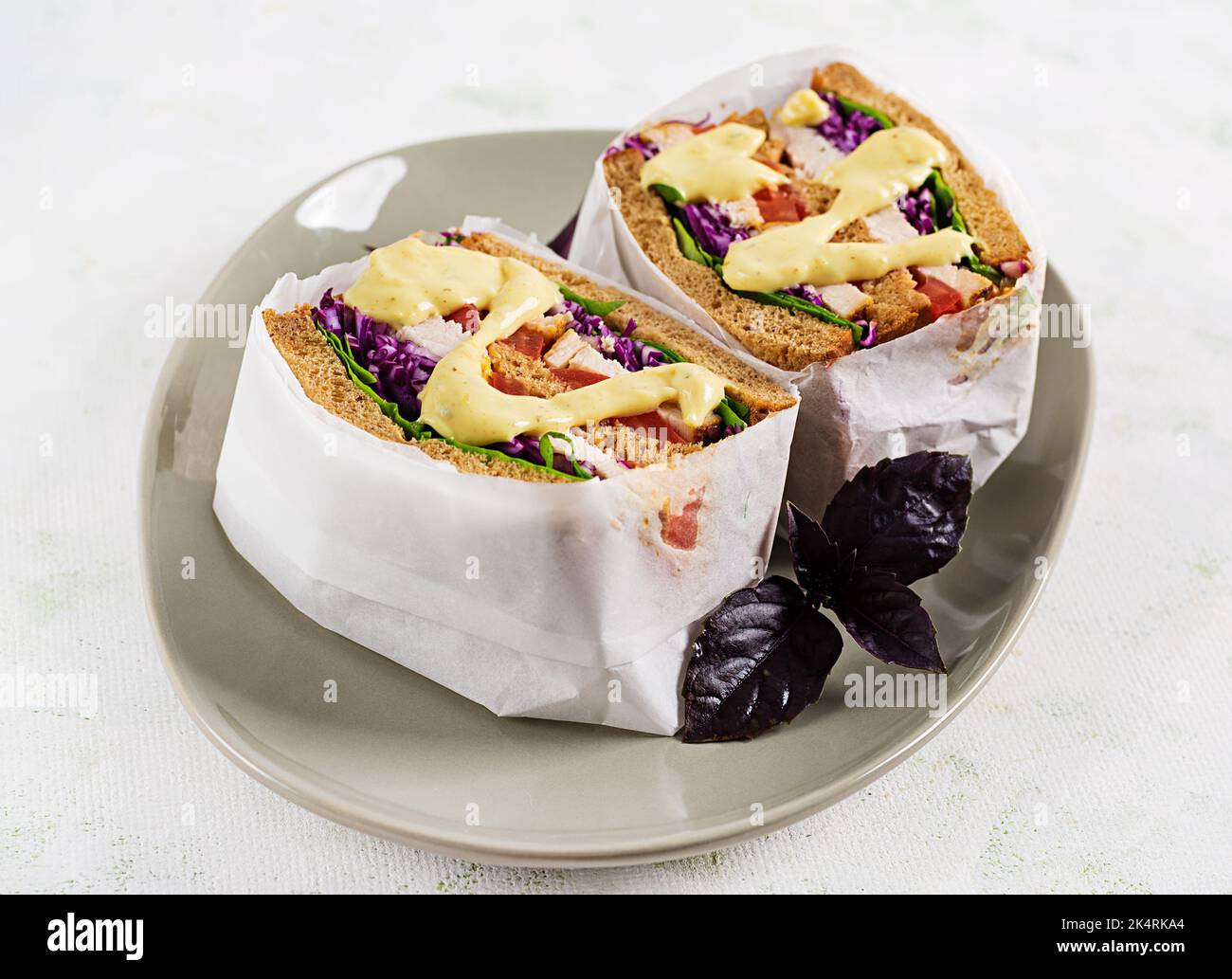 Sandwich con filetto di pollo, cavolo rosso e salsa, avvolto in carta. Prendi. Foto Stock