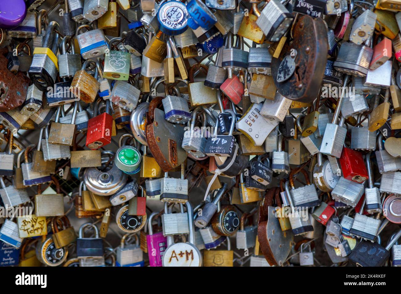 Lucchetti vecchi e nuovi con nomi e date scritte su di essi si bloccano su un ponte come segno d'amore a San Antonio, Texas. Foto Stock