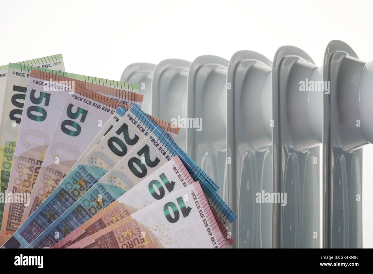 Banconote in euro sulla batteria del radiatore di riscaldamento. Concetto di costi di riscaldamento costosi e di aumento della bolletta energetica Foto Stock