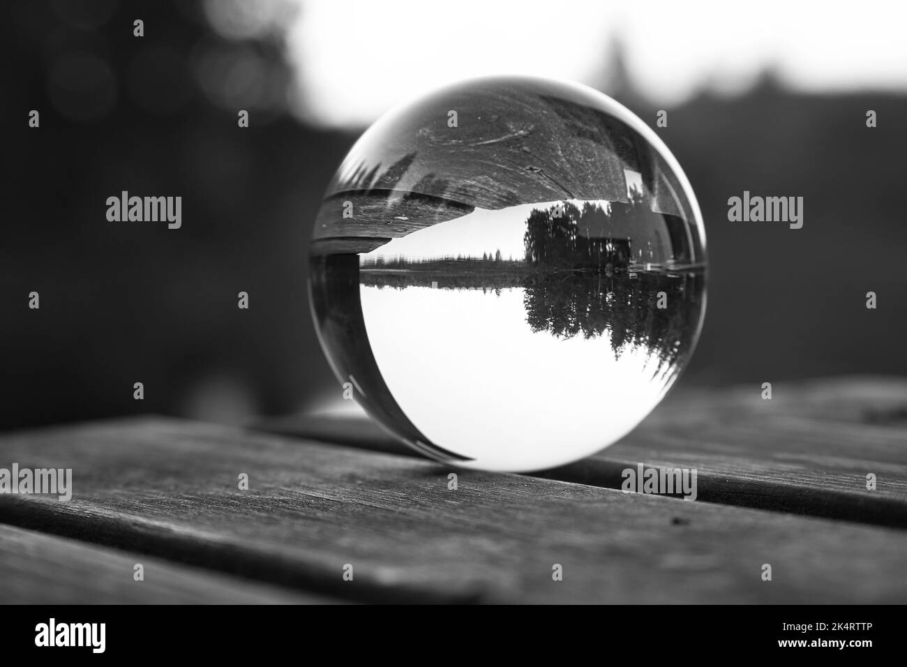 Palla di vetro su un molo di legno presso un lago svedese al crepuscolo in bianco e nero. Foto della natura dalla Scandinavia Foto Stock